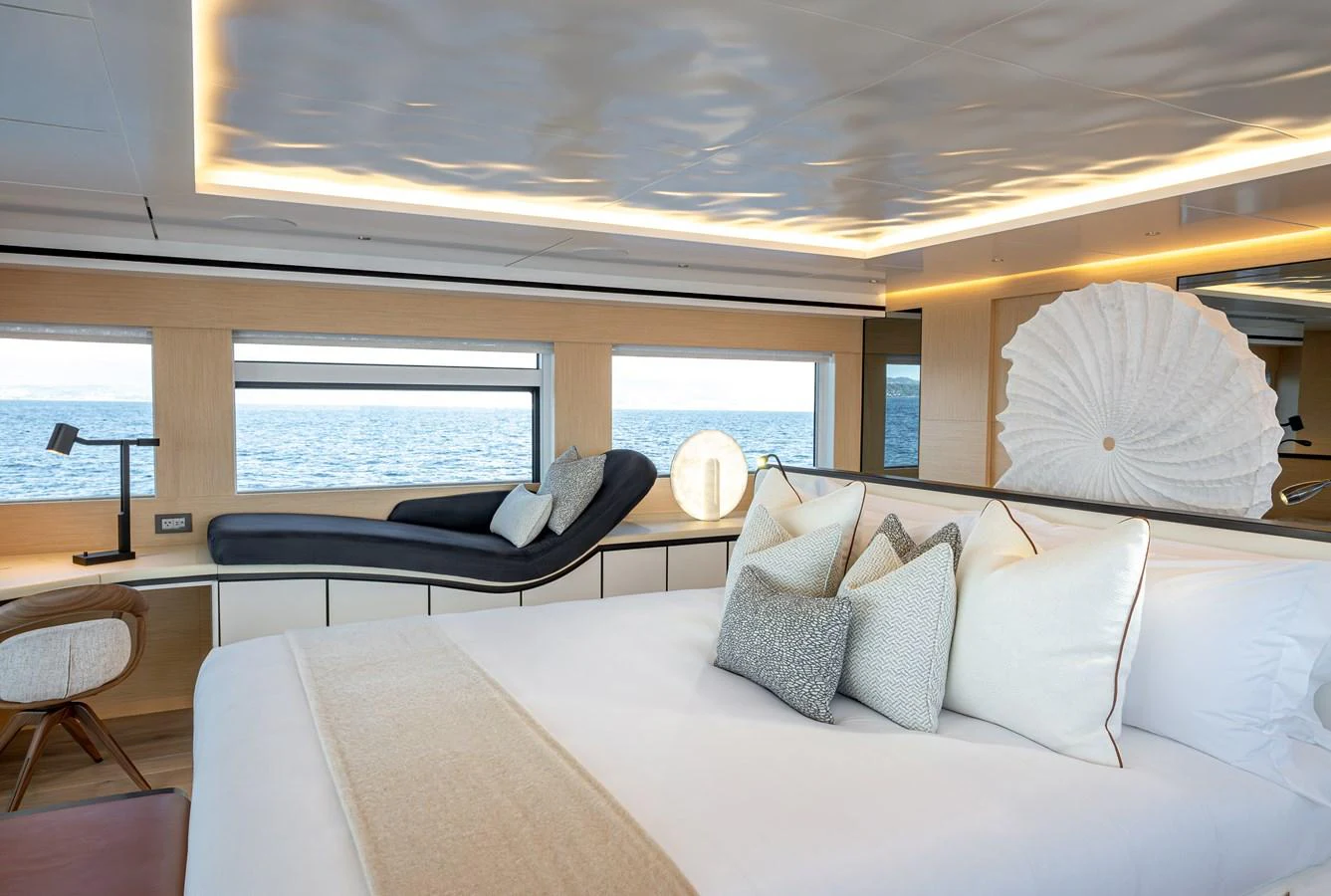 The stateroom features a luxurious bed with plush pillows and a chaise lounge by the window, offering a serene view of the sea. aboard NUMARINE 37XP#22 Yacht for Sale