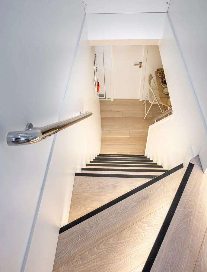 A sleek and modern staircase leads to the lower deck of the yacht, showcasing elegant wooden steps and a polished handrail. aboard NUMARINE 37XP#22 Yacht for Sale