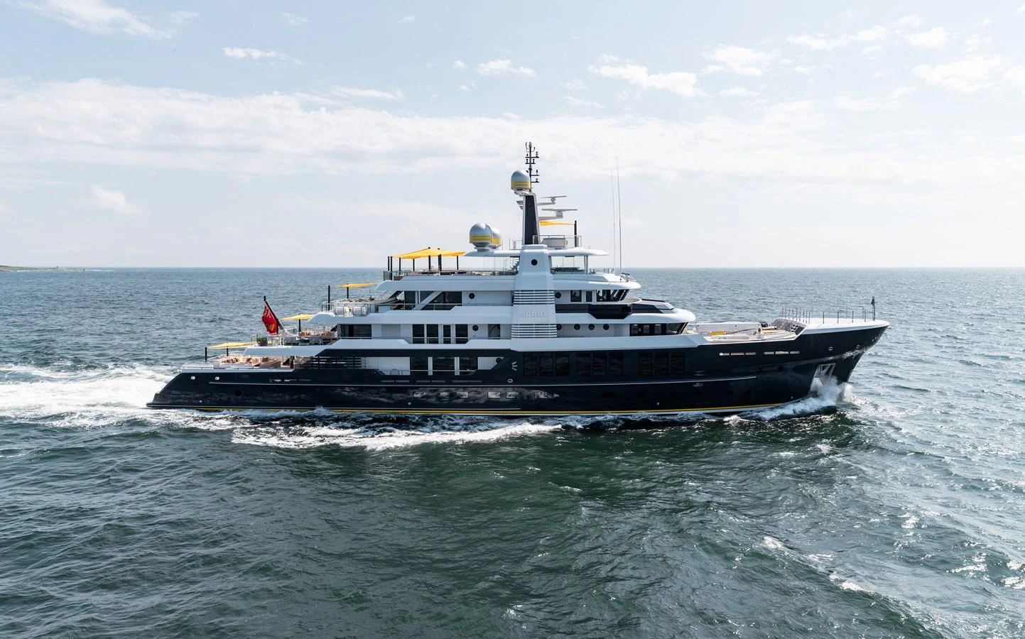 A luxurious yacht cruises through open waters under a clear sky. aboard SCOUT Yacht for Sale