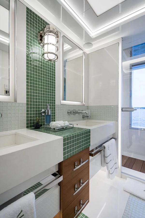 A modern yacht bathroom featuring green mosaic tiles and sleek fixtures. aboard SCOUT Yacht for Sale