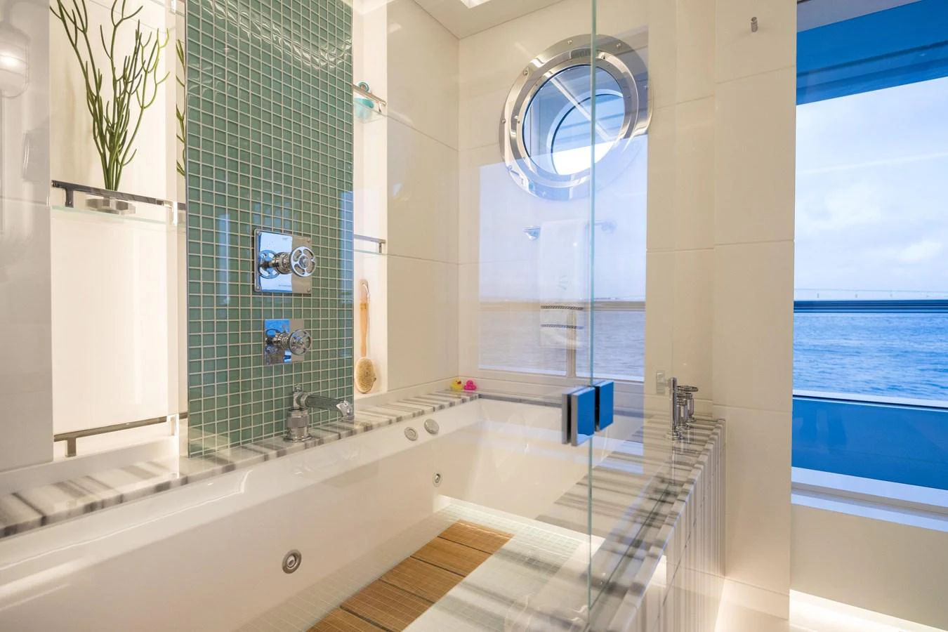 A luxurious bathroom with a large bathtub and a view of the ocean through a porthole window. aboard SCOUT Yacht for Sale
