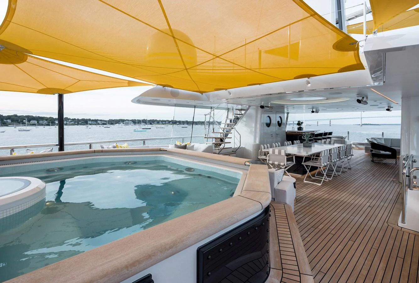 The sundeck features a luxurious hot tub and ample seating under stylish yellow sunshades. aboard SCOUT Yacht for Sale