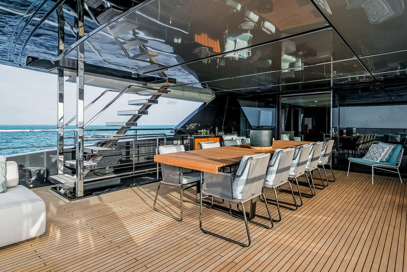 The aft deck features a spacious dining area with a large table and comfortable seating, perfect for alfresco meals with a view of the sea. aboard RIVA 130/02 Yacht for Sale