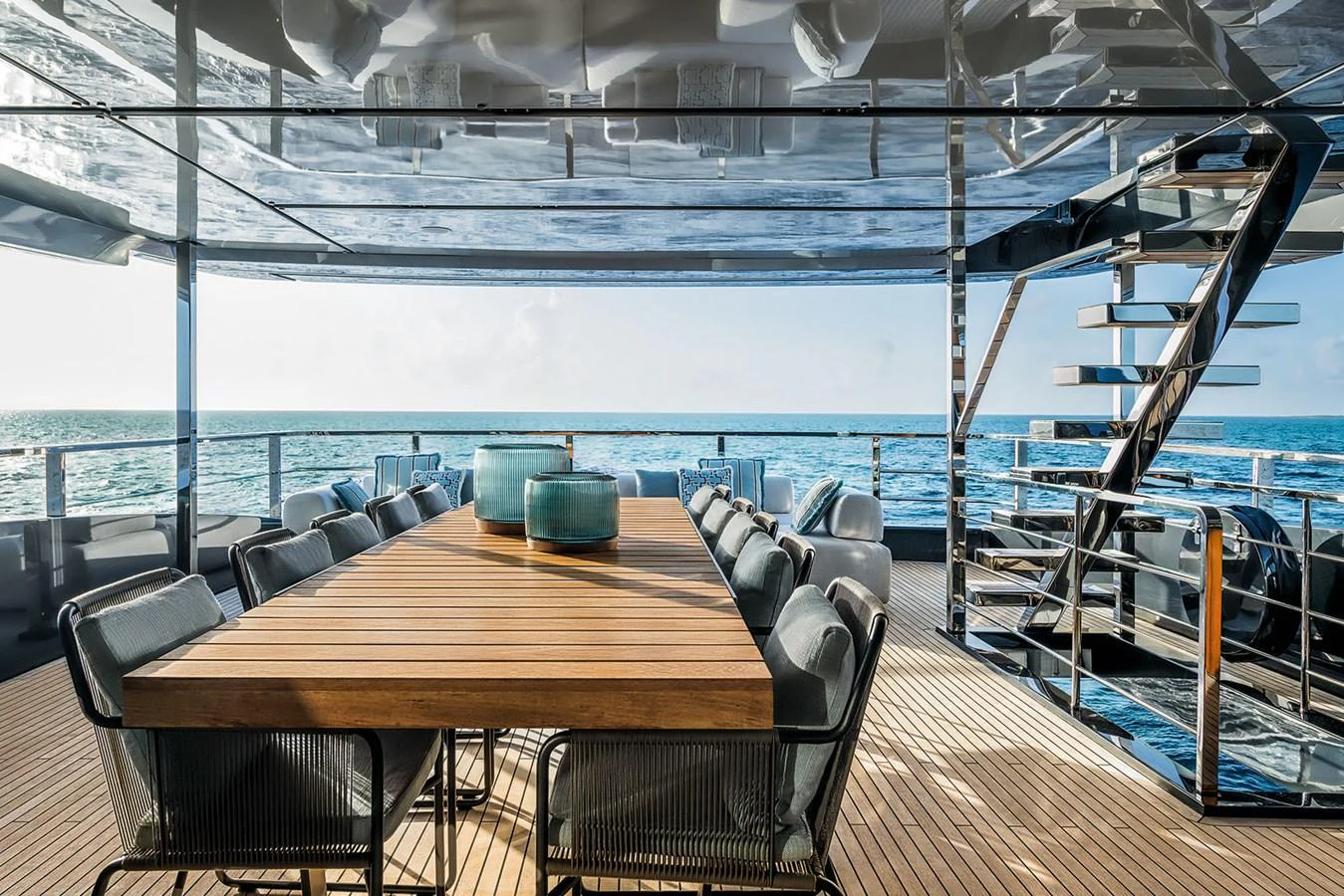 The aft deck features a spacious dining area with a large wooden table and comfortable seating, perfect for alfresco dining with ocean views. aboard RIVA 130/02 Yacht for Sale
