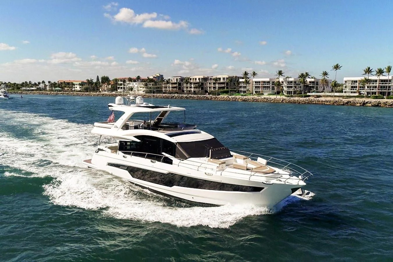 A sleek and modern yacht cruises through clear blue waters with a scenic coastal backdrop. aboard GALEON Yacht for Sale