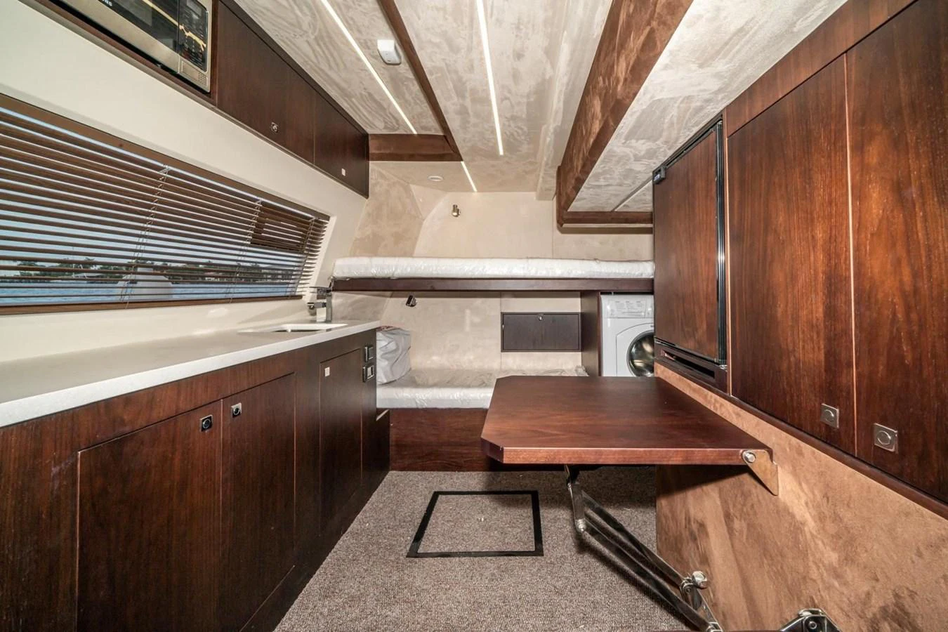 The yacht's interior features a cozy and functional space with dark wood cabinetry and a foldable table. aboard GALEON Yacht for Sale
