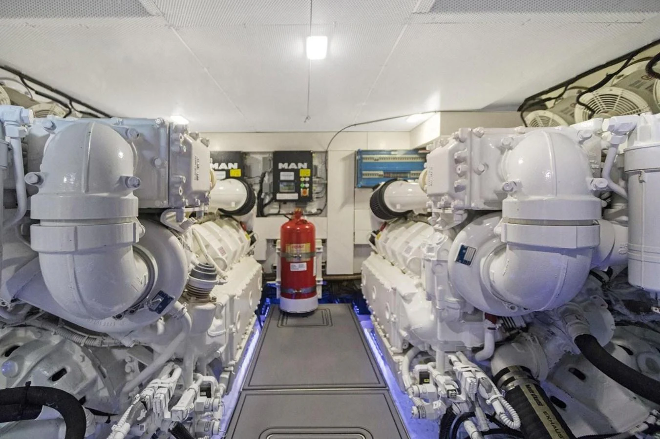 The image showcases the yacht's pristine engine room with powerful machinery and a fire extinguisher in the center. aboard GALEON Yacht for Sale