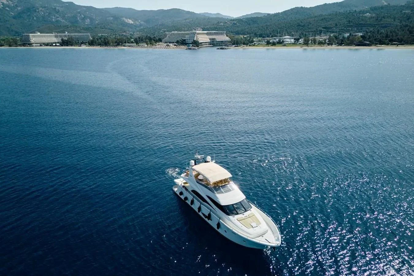 A sleek yacht cruises on calm waters with a scenic coastal backdrop. aboard MARQUIS 720 Yacht for Sale