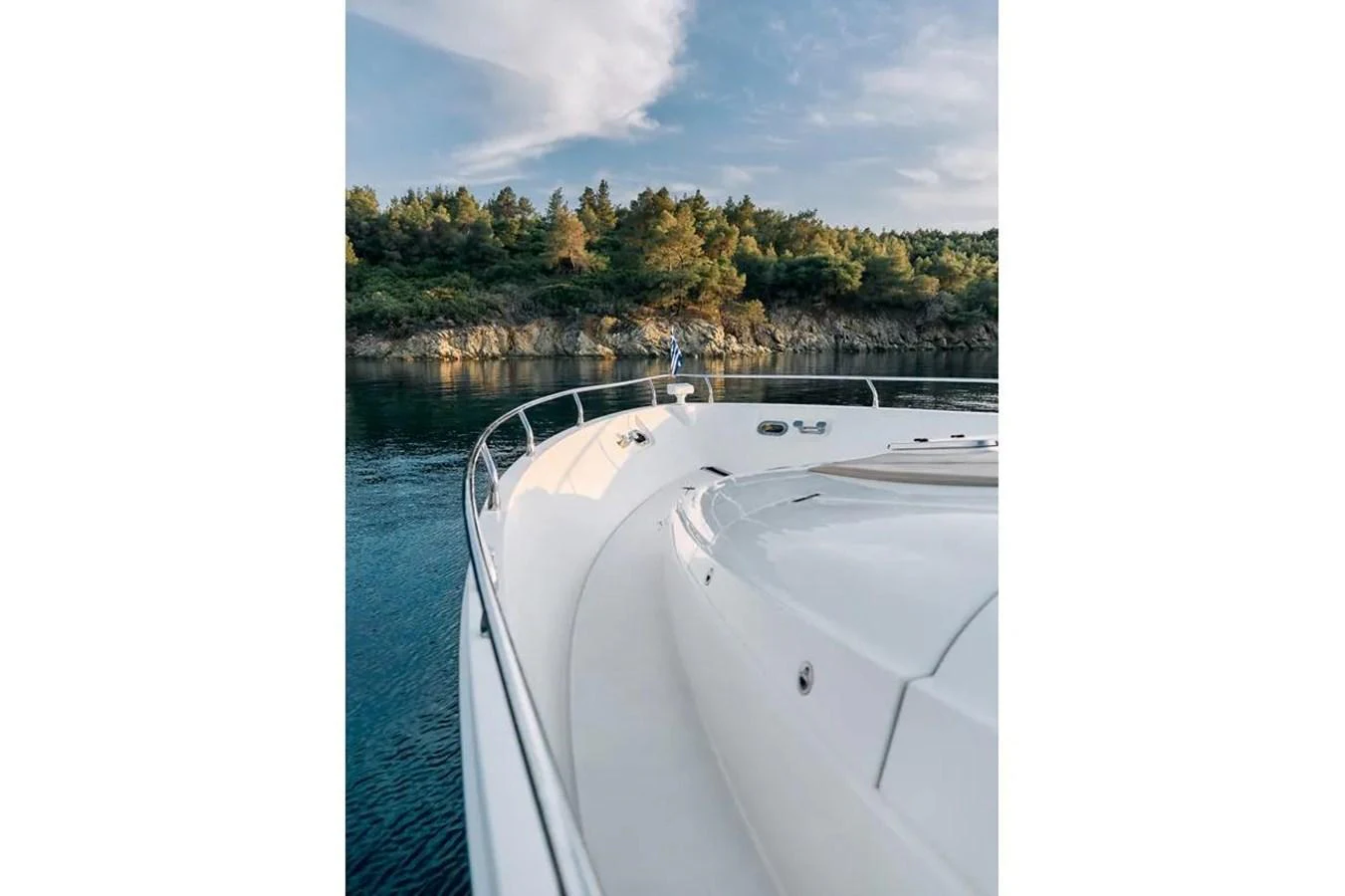 The sleek bow of the yacht glides through serene waters, framed by a picturesque coastline. aboard MARQUIS 720 Yacht for Sale