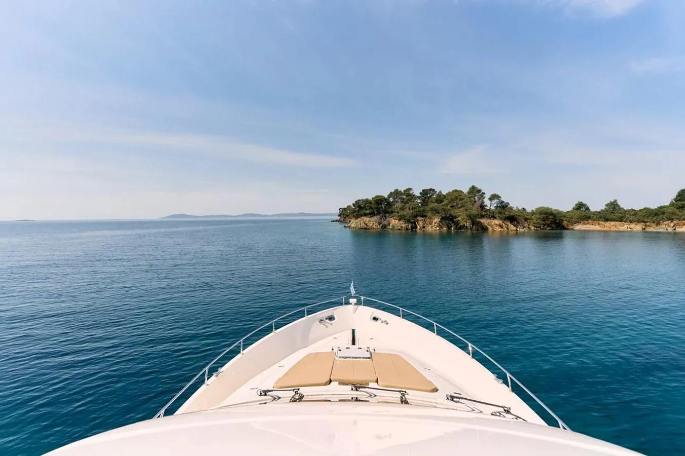 The yacht's bow gracefully approaches a serene island, showcasing a tranquil cruising experience. aboard MARQUIS 720 Yacht for Sale