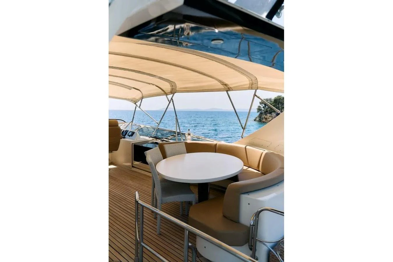 The aft deck features a stylish seating area with a round table, perfect for alfresco dining with a view of the sea. aboard MARQUIS 720 Yacht for Sale