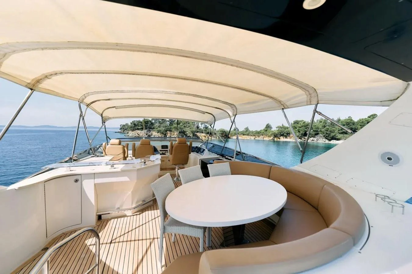 The flybridge offers a spacious seating area with a round table, perfect for alfresco dining and relaxation. aboard MARQUIS 720 Yacht for Sale