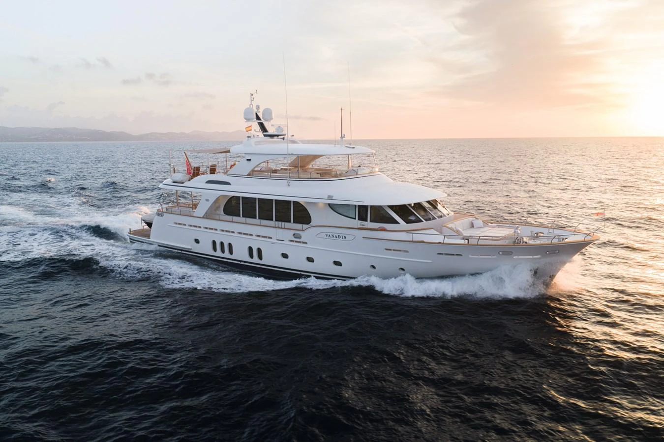 A luxurious yacht cruises through the open sea at sunset, showcasing its elegant design and spacious decks. aboard VANADIS Yacht for Sale