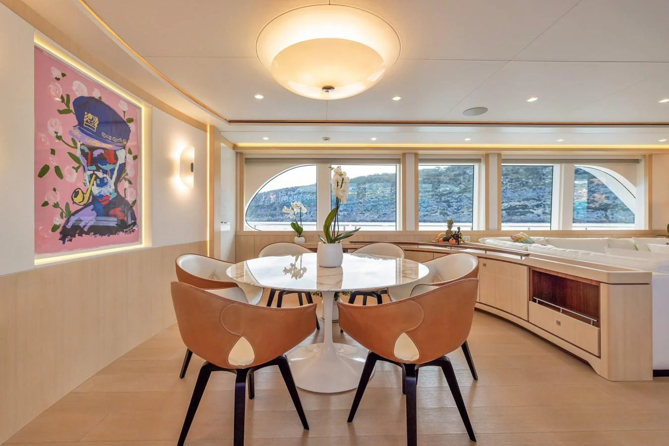 The yacht's dining area features a modern table with stylish chairs, complemented by large windows offering scenic views. aboard VANADIS Yacht for Sale