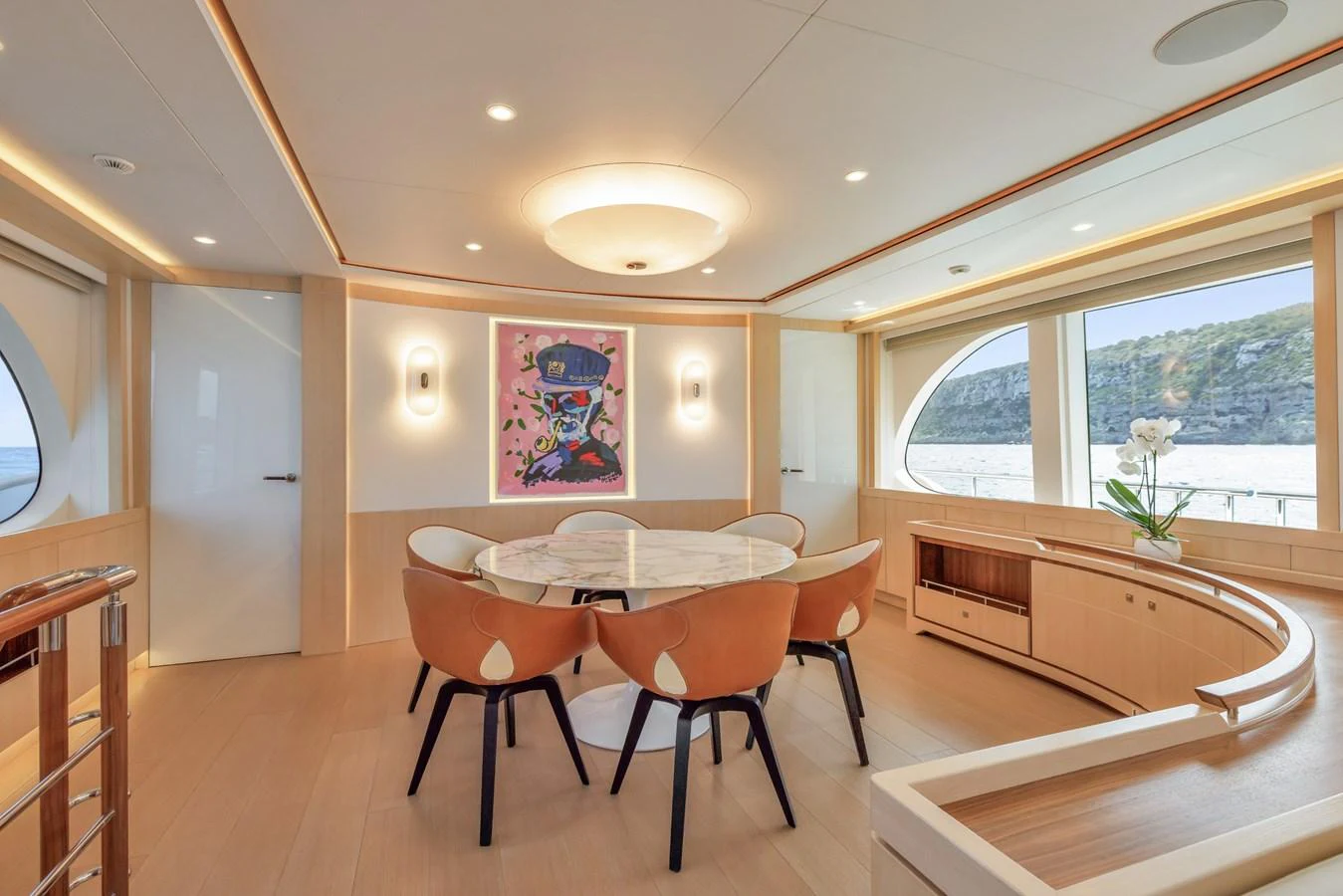 The yacht's dining area features a modern table surrounded by stylish chairs, with large windows offering scenic views. aboard VANADIS Yacht for Sale