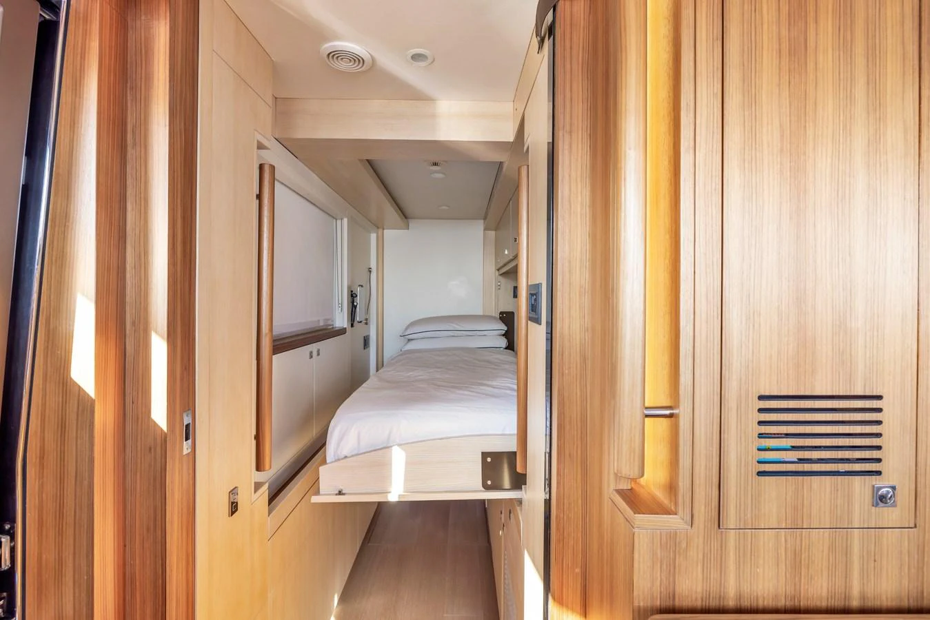The image showcases a cozy and well-lit cabin with a comfortable bed and wooden finishes. aboard VANADIS Yacht for Sale