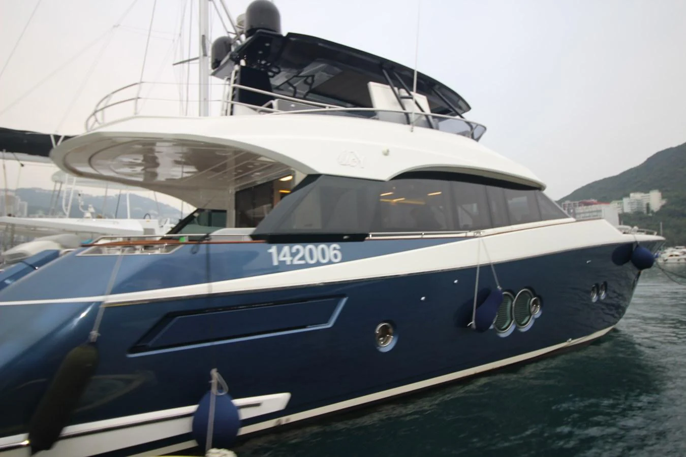 A sleek and modern yacht with a blue hull and white superstructure is docked in a marina. aboard AURORA Yacht for Sale