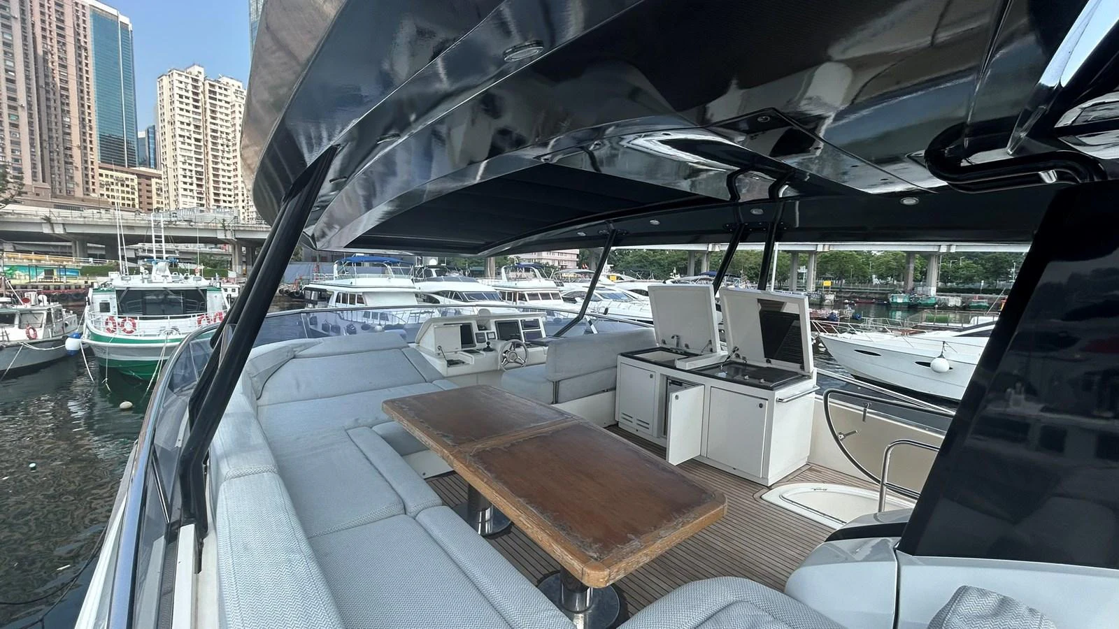 The flybridge offers a spacious seating area with a wooden table and modern helm station, perfect for enjoying the view. aboard AURORA Yacht for Sale