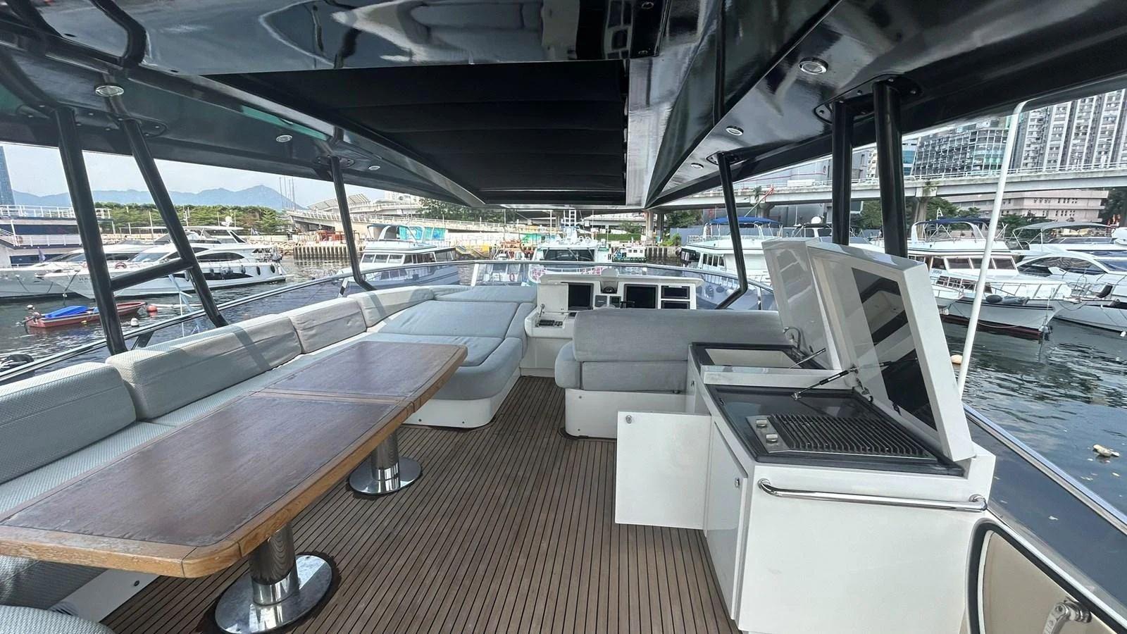 The flybridge offers a spacious and luxurious outdoor seating area with a dining table and a grill station. aboard AURORA Yacht for Sale