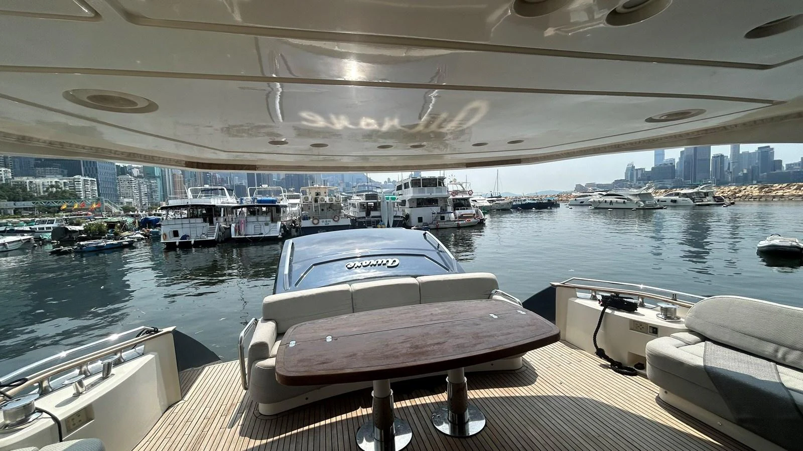 The aft deck offers a comfortable seating area with a wooden table, perfect for enjoying the marina view. aboard AURORA Yacht for Sale