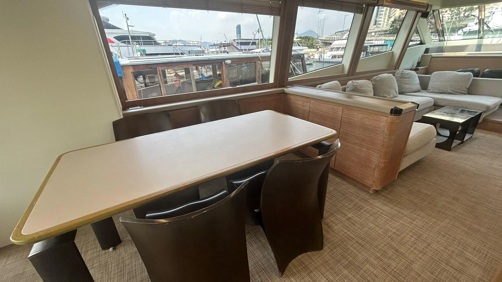 The salon features a comfortable seating area and a dining table with a view of the marina. aboard AURORA Yacht for Sale