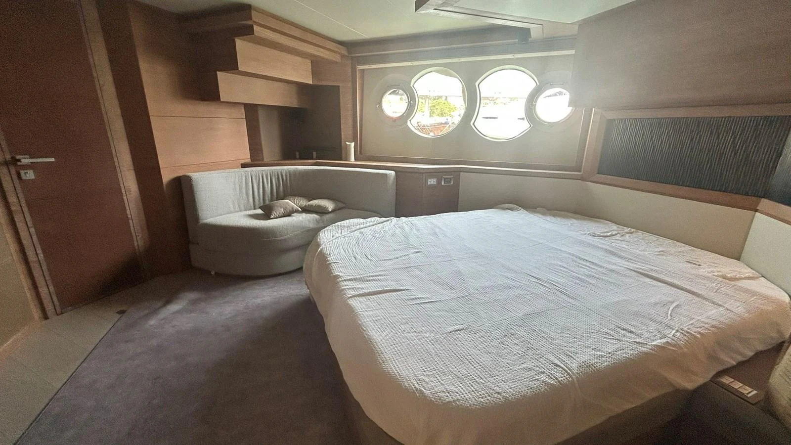 A cozy stateroom with a large bed and circular windows offering a serene view. aboard AURORA Yacht for Sale