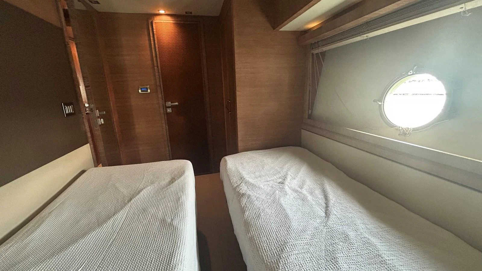 The guest stateroom features twin beds and a porthole window for natural light. aboard AURORA Yacht for Sale