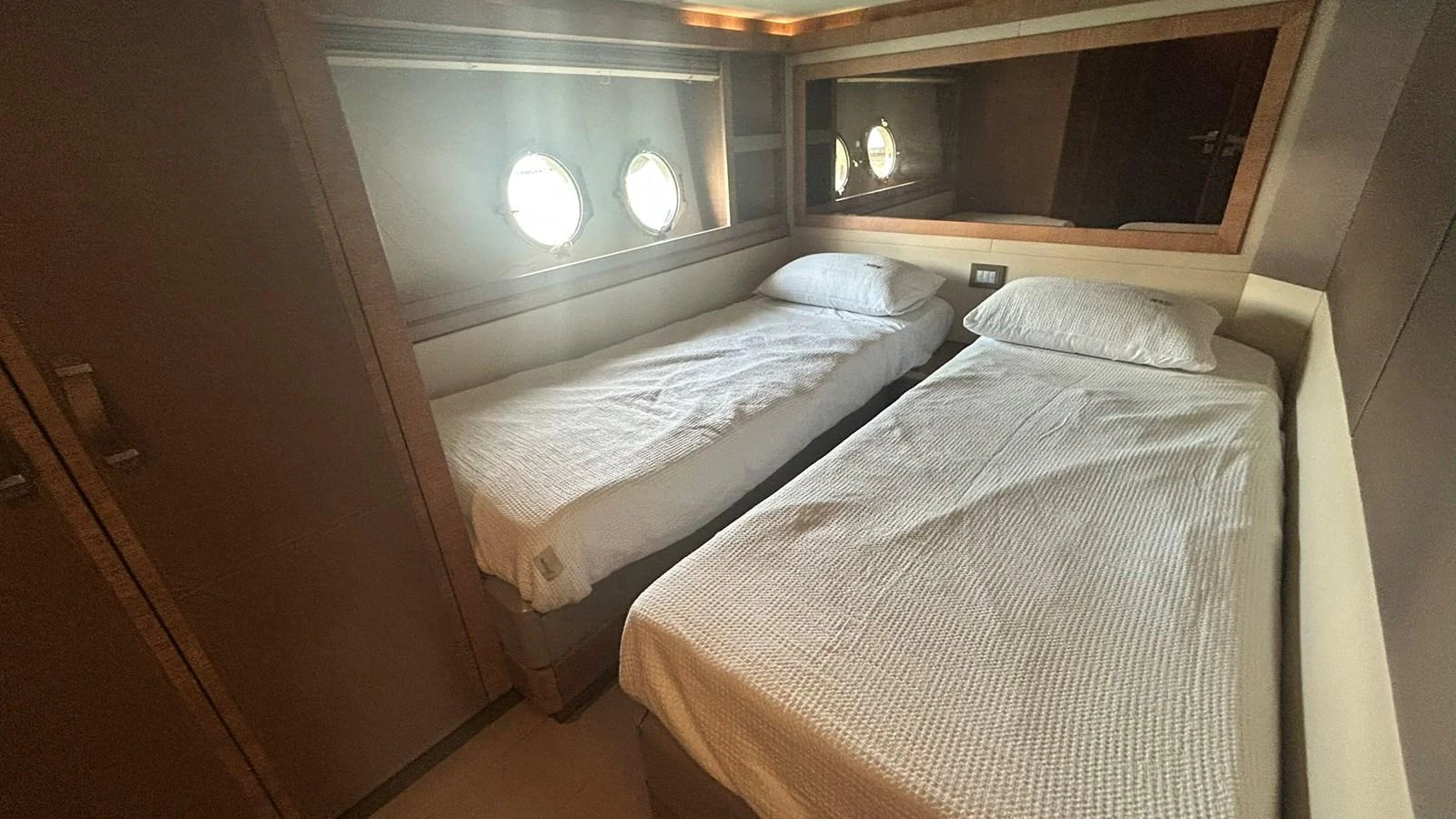A cozy twin stateroom with two single beds and porthole windows providing natural light. aboard AURORA Yacht for Sale