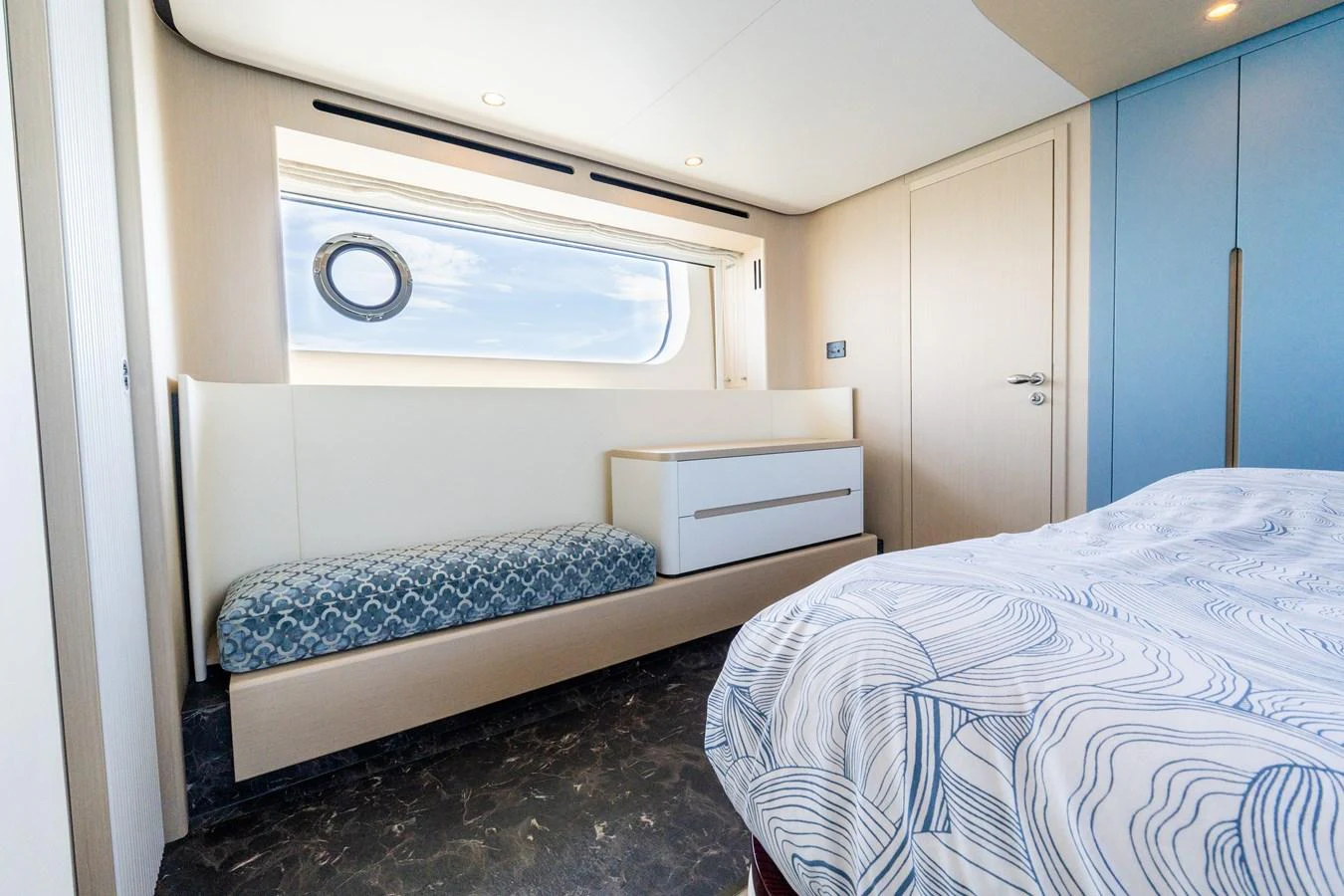 A cozy stateroom featuring a bed and a seating area with a view through a porthole. aboard GONE PHISHING Yacht for Sale