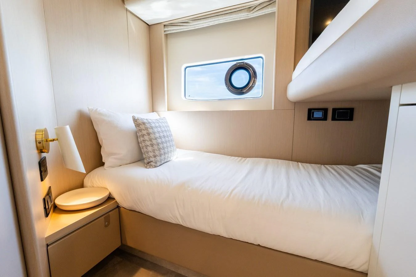 A cozy guest cabin with a single bed and a porthole window. aboard GONE PHISHING Yacht for Sale