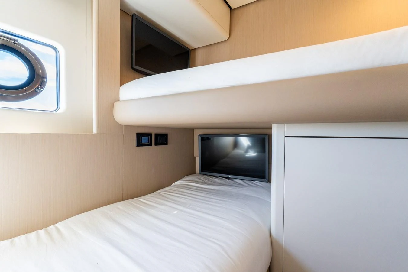 The guest cabin features cozy bunk beds with a modern design and natural light from a porthole. aboard GONE PHISHING Yacht for Sale
