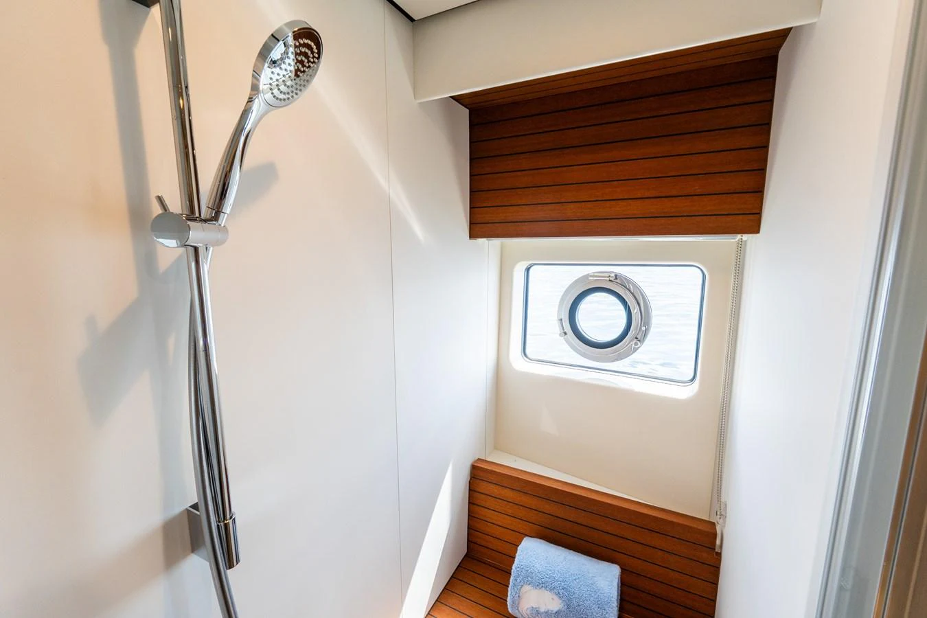 This yacht's shower area features a sleek design with a wooden bench and a porthole window. aboard GONE PHISHING Yacht for Sale