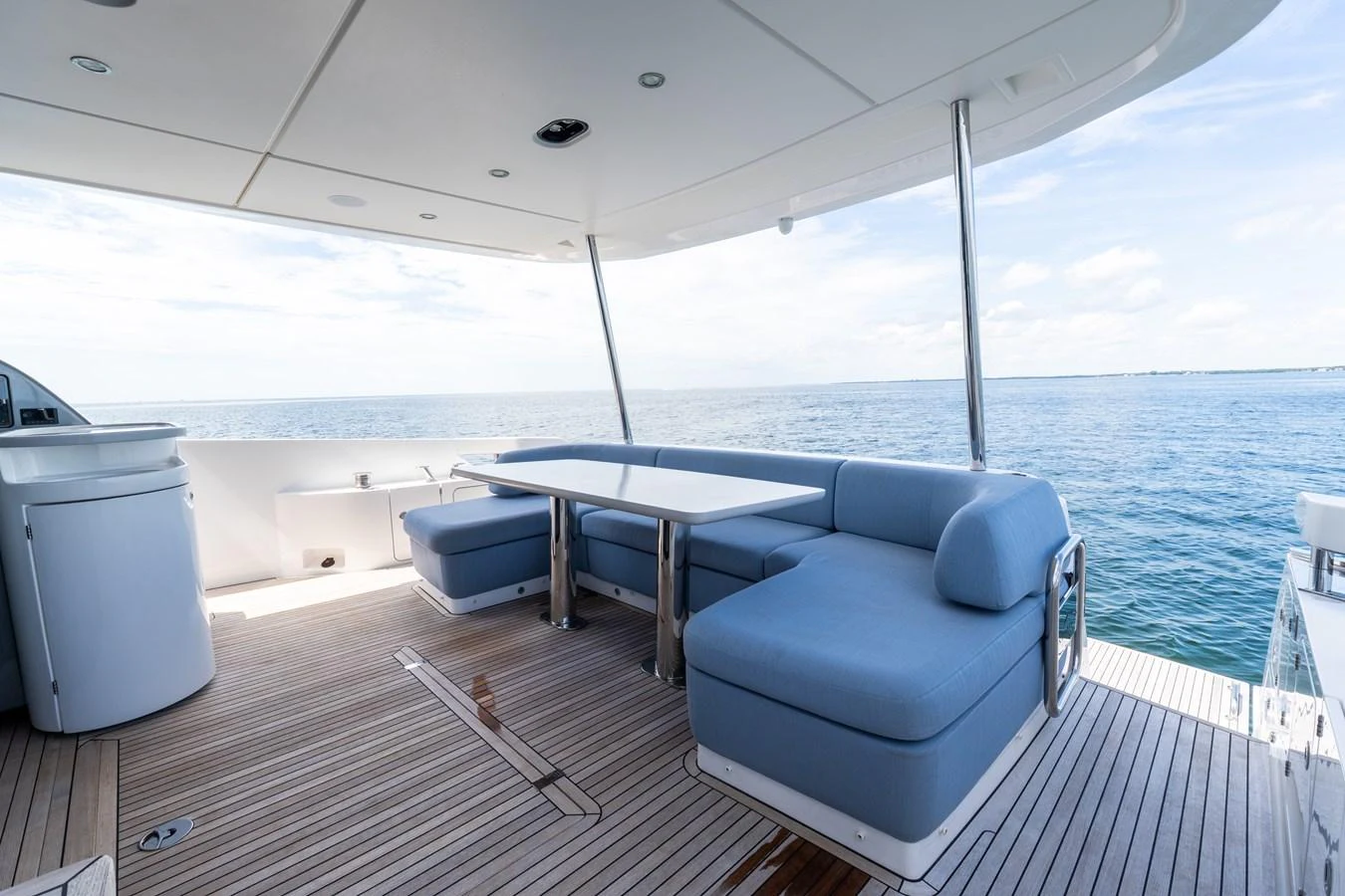 The aft deck features comfortable seating and a dining table with a stunning ocean view. aboard GONE PHISHING Yacht for Sale