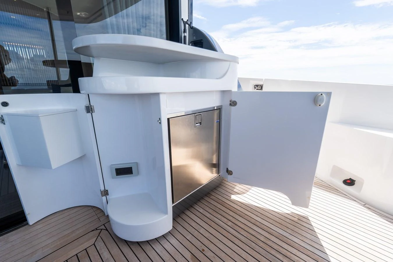 A sleek outdoor bar area with a stainless steel refrigerator and white cabinetry on a yacht. aboard GONE PHISHING Yacht for Sale
