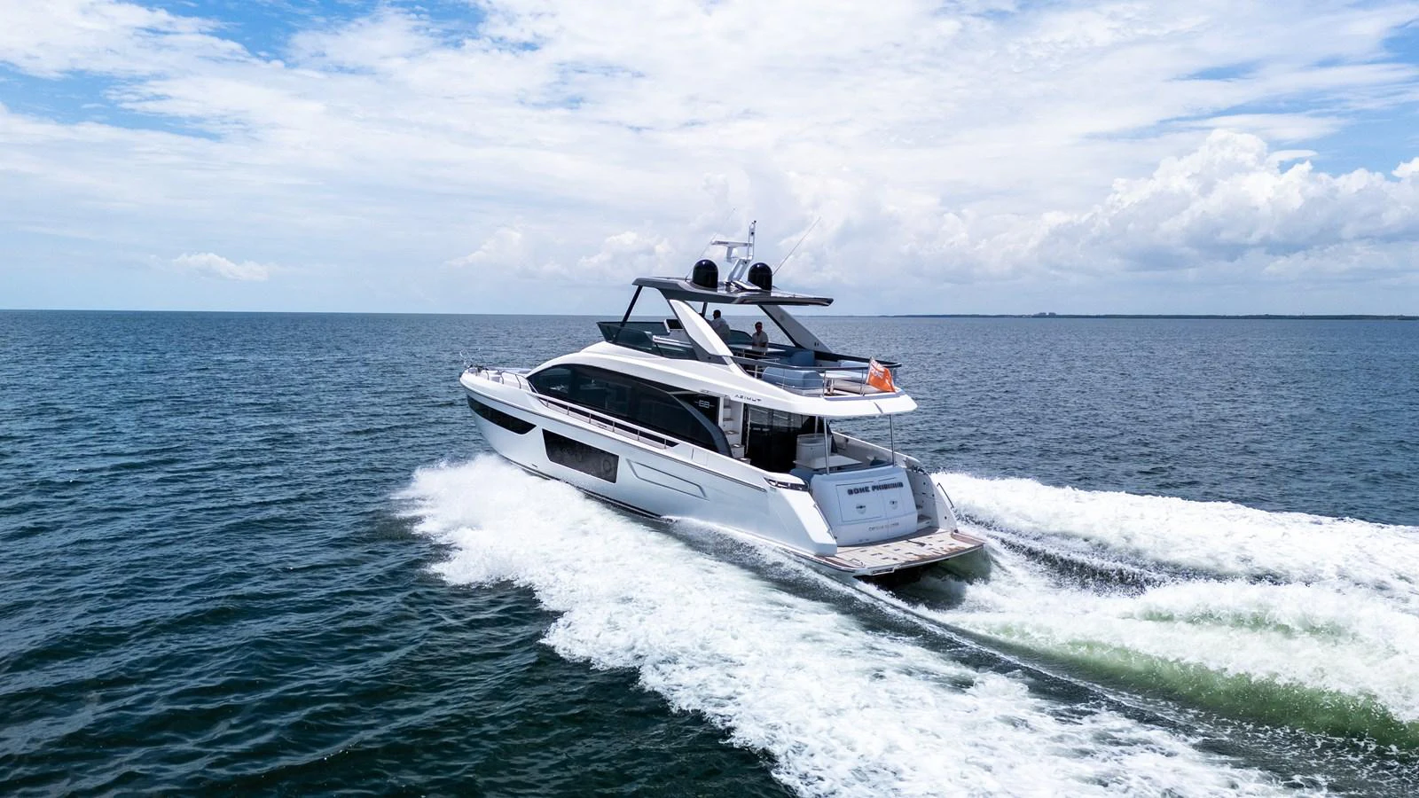 A sleek yacht cruises swiftly over calm waters under a partly cloudy sky. aboard GONE PHISHING Yacht for Sale
