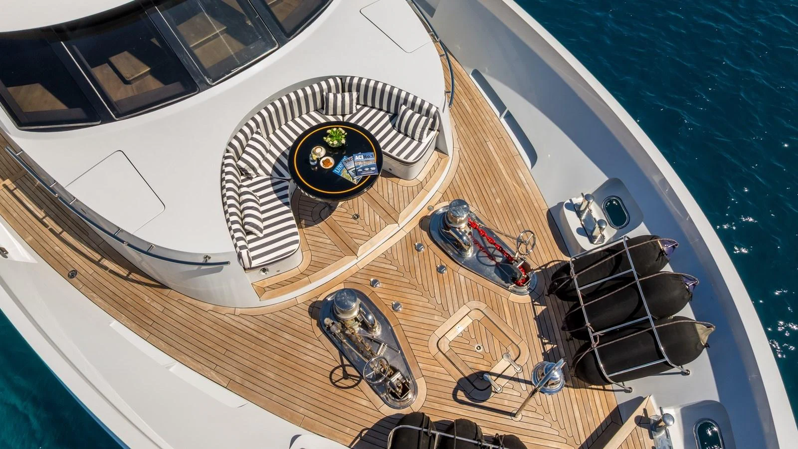 The foredeck features a stylish seating area with a striped cushion arrangement and a central table, perfect for enjoying the ocean views. aboard LA STELLA DEI MARI Yacht for Sale