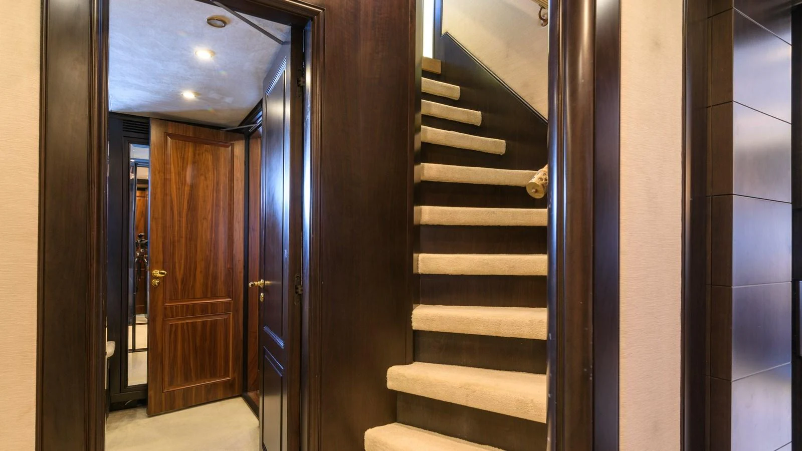 A luxurious staircase with rich wood paneling and plush carpeting leads to the upper deck. aboard LA STELLA DEI MARI Yacht for Sale