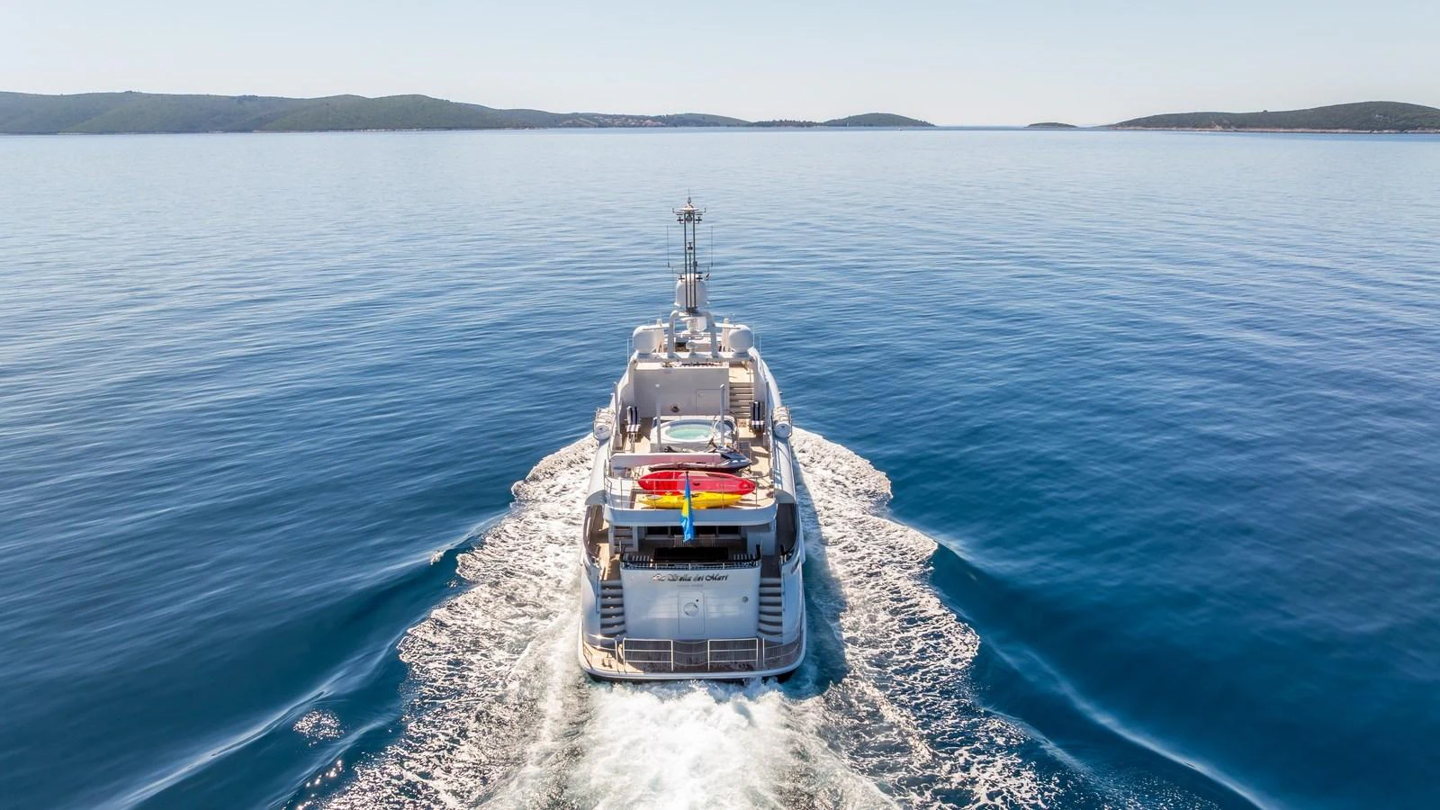 The yacht cruises smoothly on calm waters, showcasing its sleek design and vibrant water toys on the aft deck. aboard LA STELLA DEI MARI Yacht for Sale