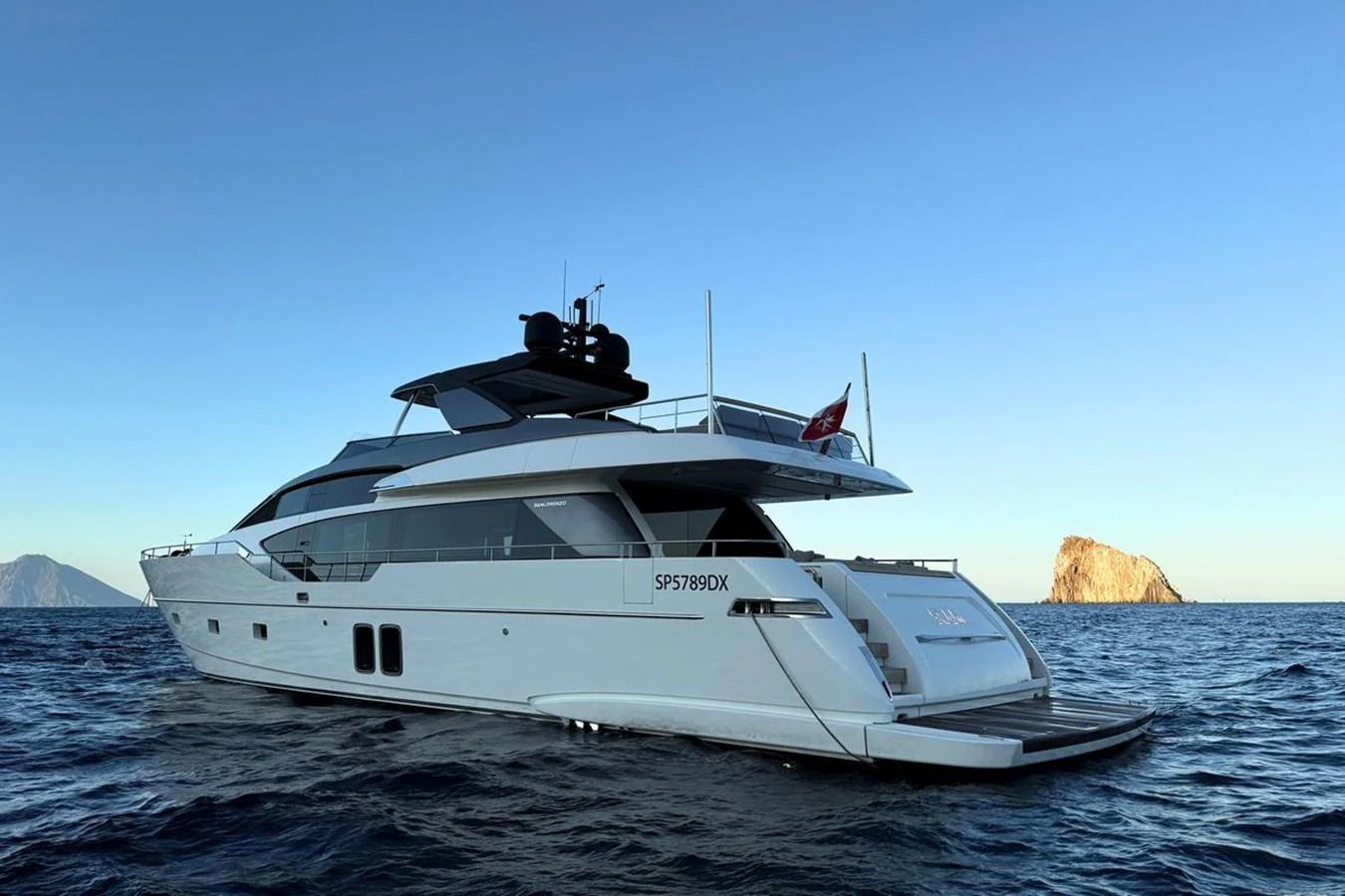 A sleek and modern yacht glides gracefully on the open sea with a serene backdrop of distant islands. aboard CUT Yacht for Sale