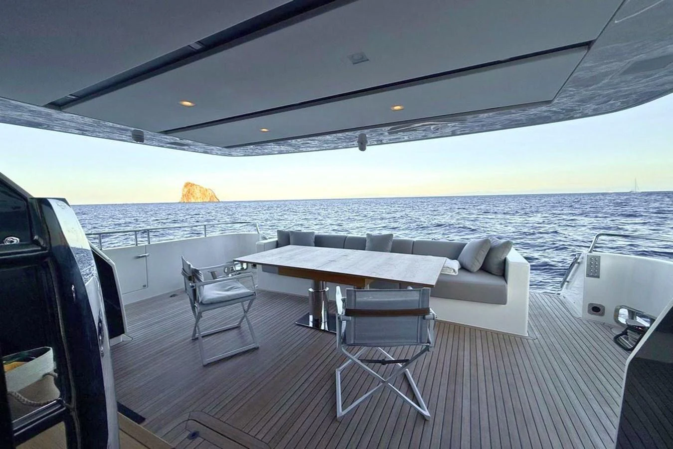 The aft deck features a spacious seating area with a dining table, offering stunning ocean views. aboard CUT Yacht for Sale