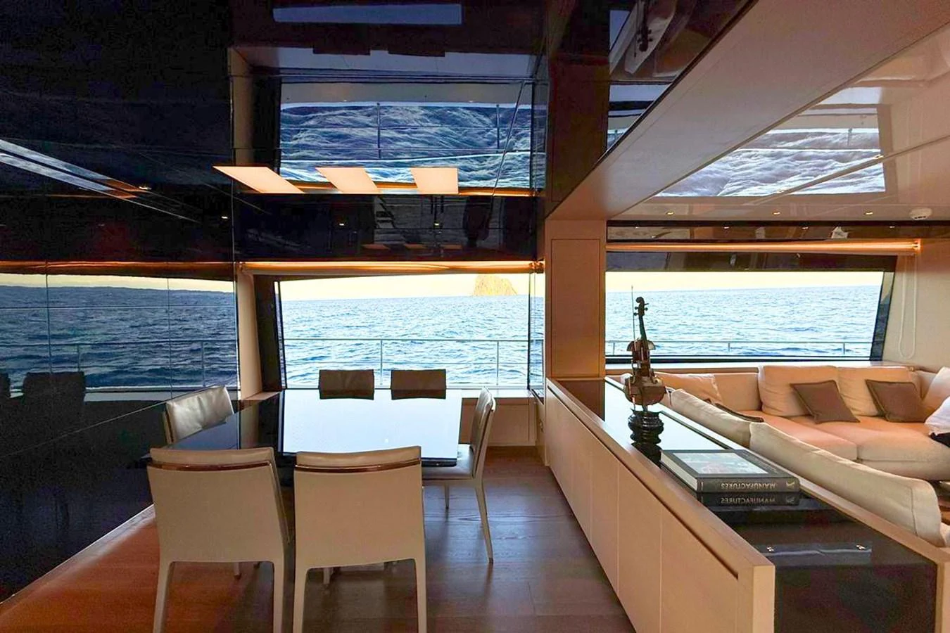 The yacht's salon features a modern dining area with a stunning ocean view through large windows. aboard CUT Yacht for Sale
