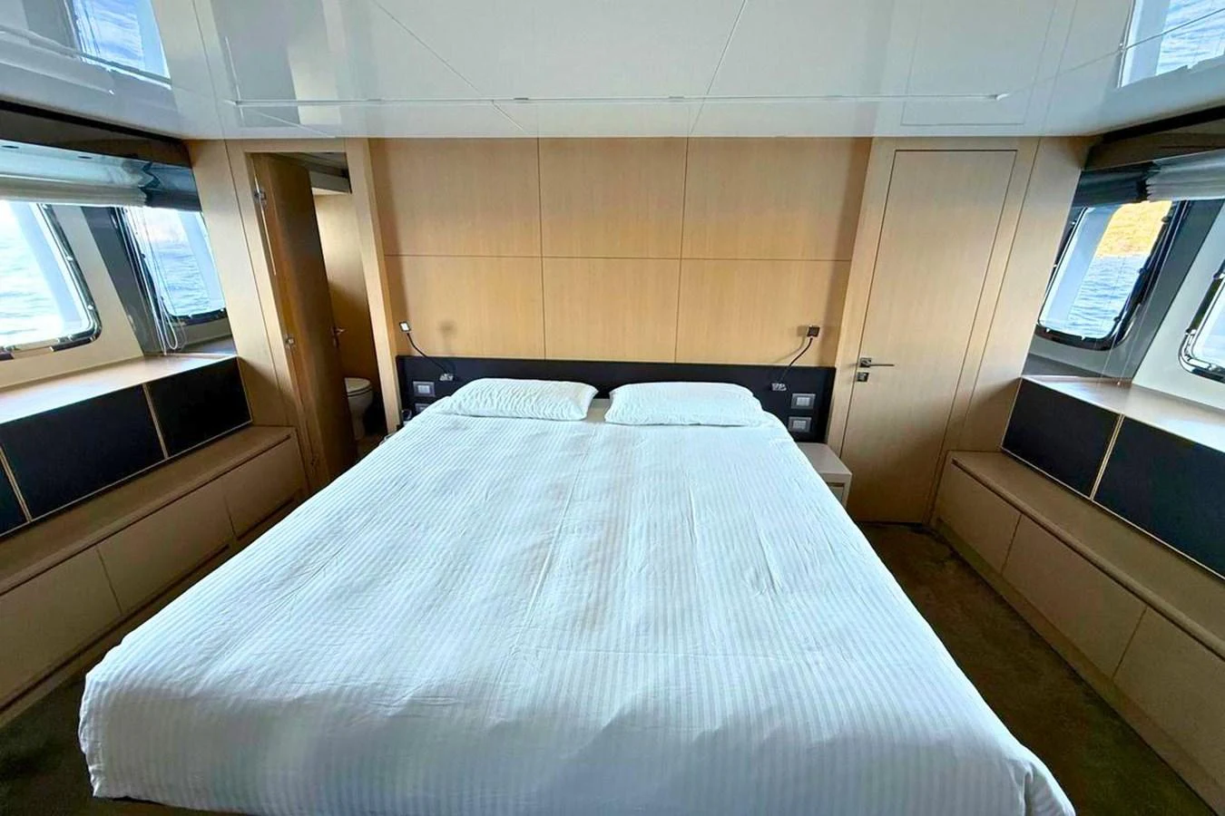 The stateroom features a spacious bed with ample natural light from large windows. aboard CUT Yacht for Sale