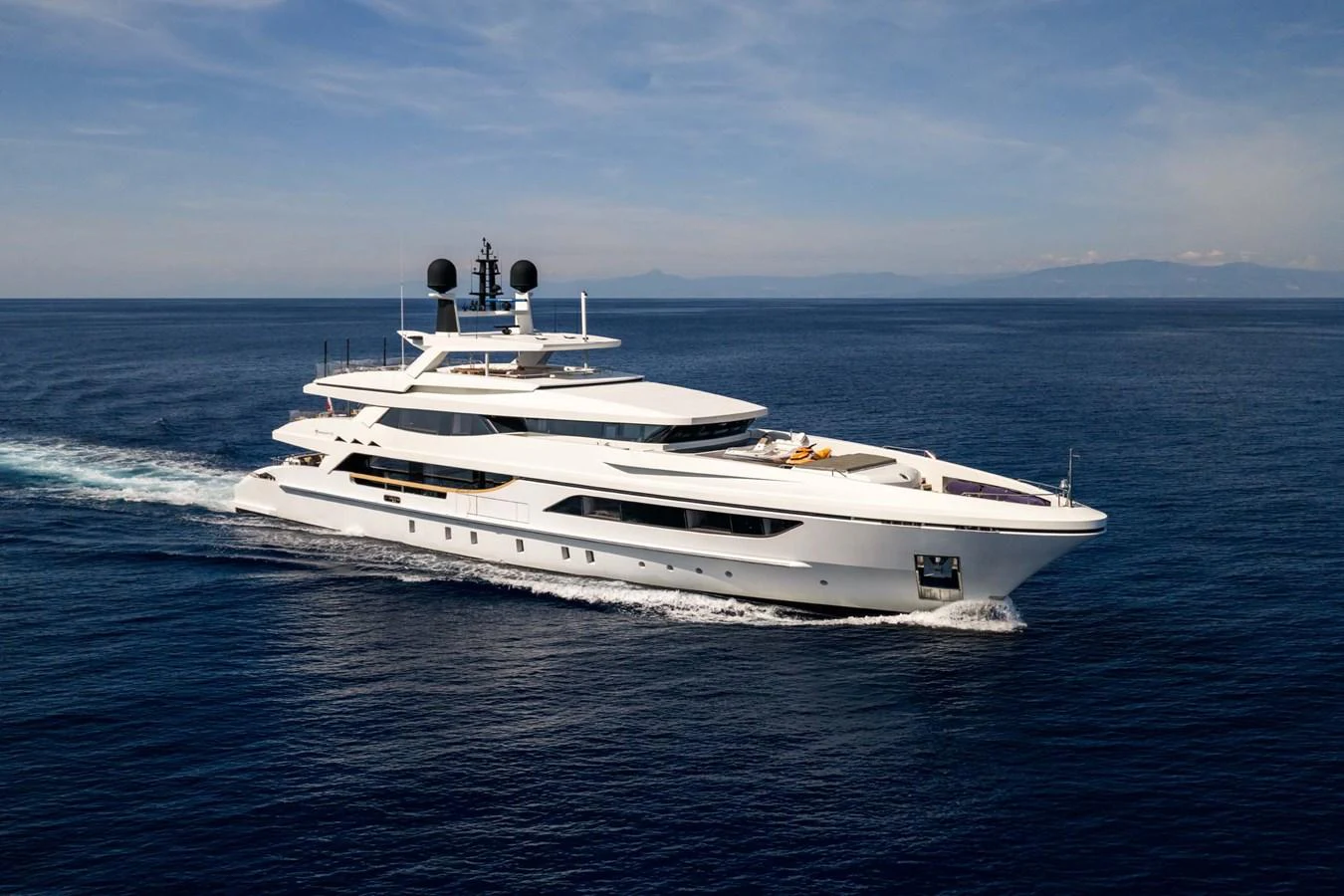 A sleek and modern yacht cruising on open waters under a clear blue sky. aboard MR. T Yacht for Sale