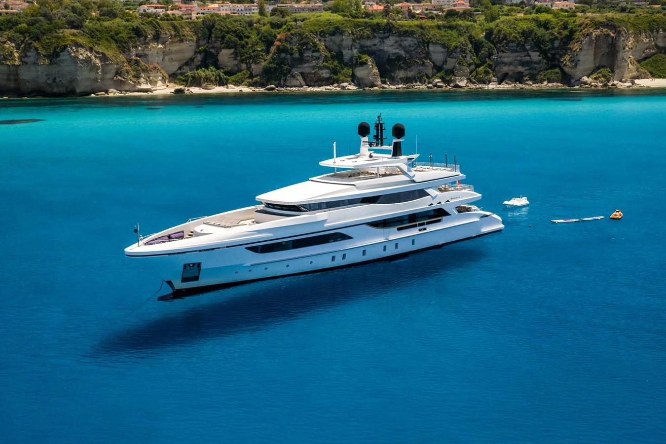 A sleek and modern yacht glides gracefully on vibrant blue waters near a picturesque coastline. aboard MR. T Yacht for Sale