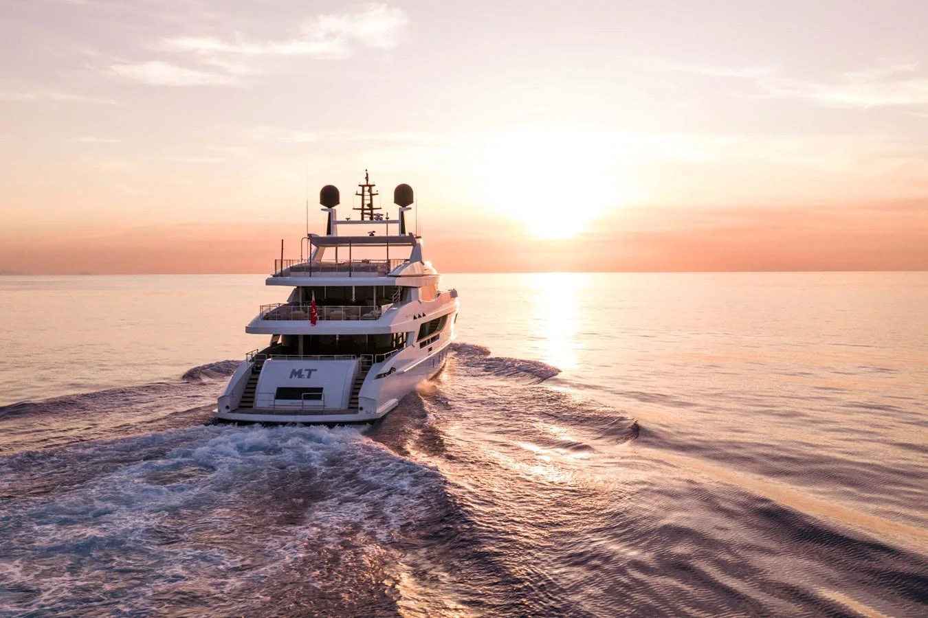 A luxurious yacht sails into the sunset, leaving a serene wake behind. aboard MR. T Yacht for Sale
