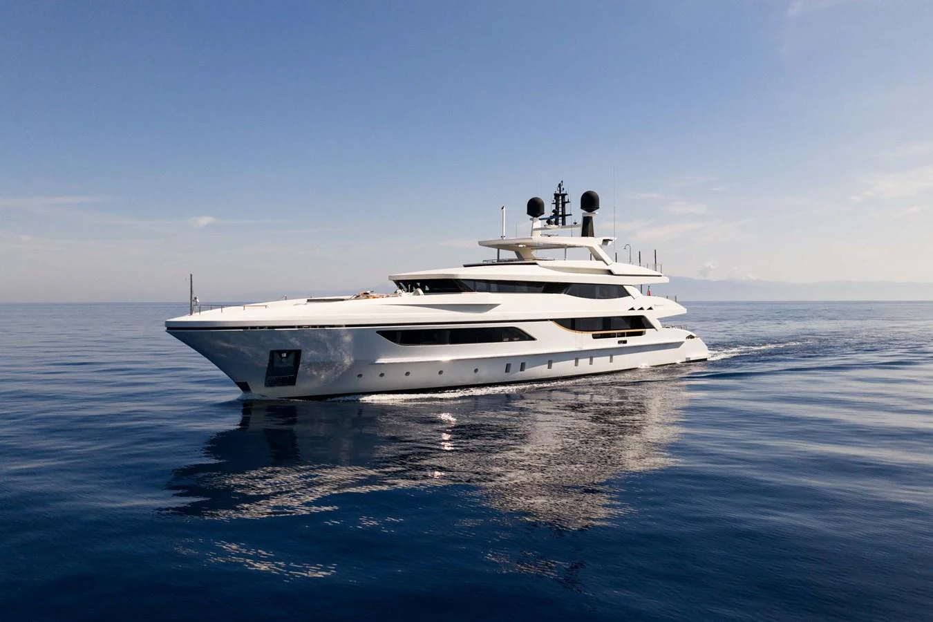 A sleek and modern yacht glides gracefully on calm waters under a clear blue sky. aboard MR. T Yacht for Sale