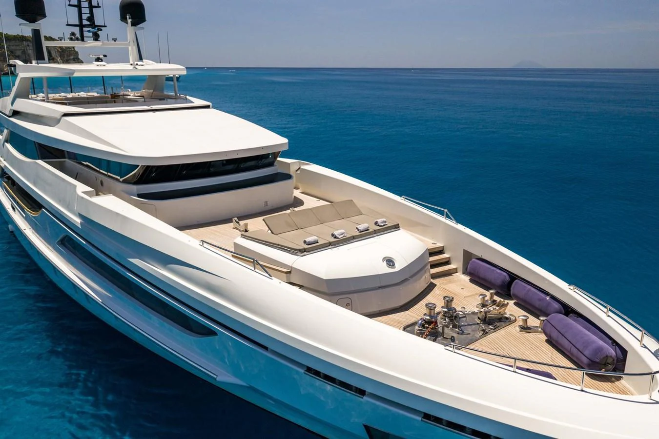 A sleek and modern yacht with spacious sunbathing areas and luxurious amenities on the deck, cruising in clear blue waters. aboard MR. T Yacht for Sale