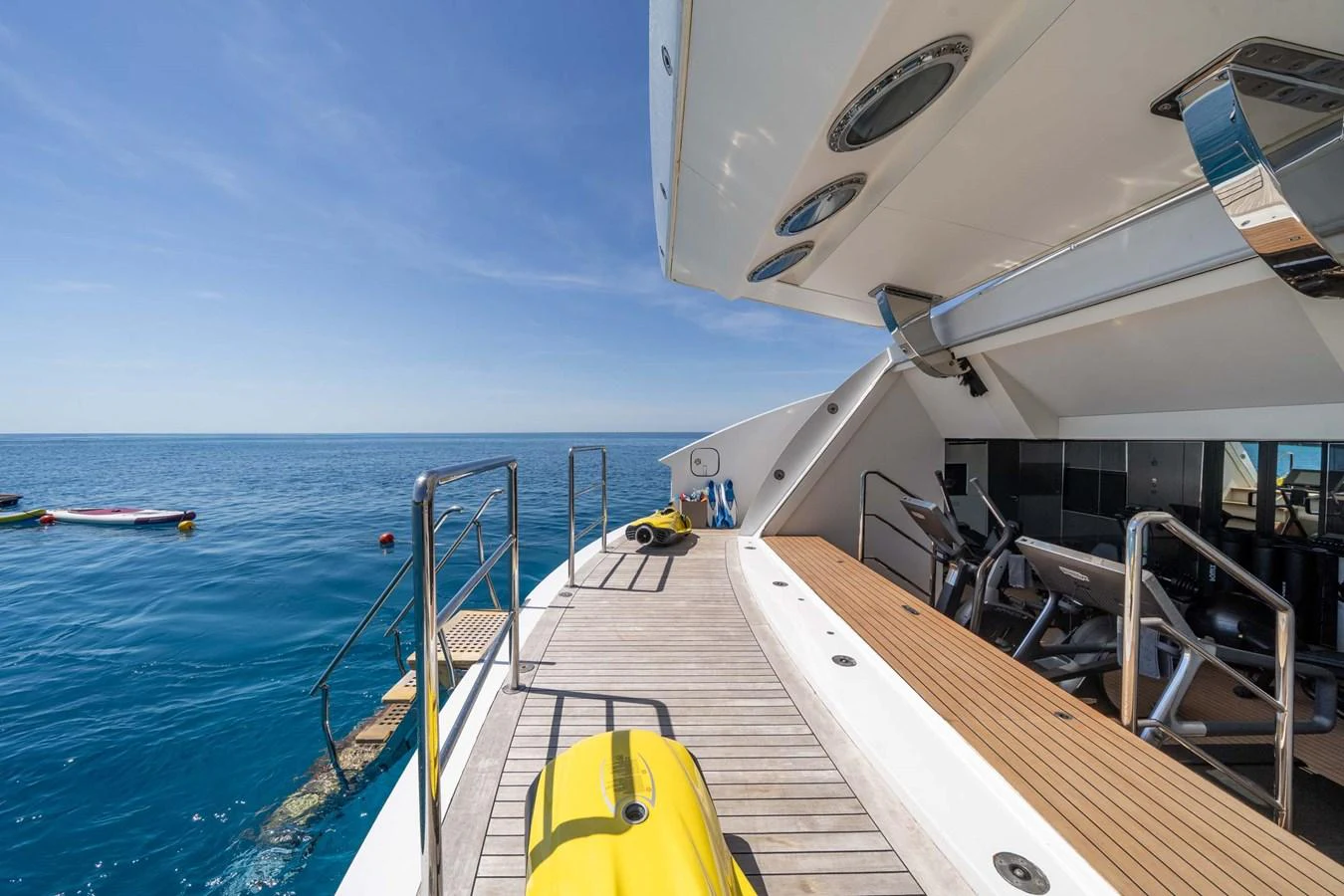 The aft deck features a spacious area with gym equipment and a view of the serene blue ocean. aboard MR. T Yacht for Sale