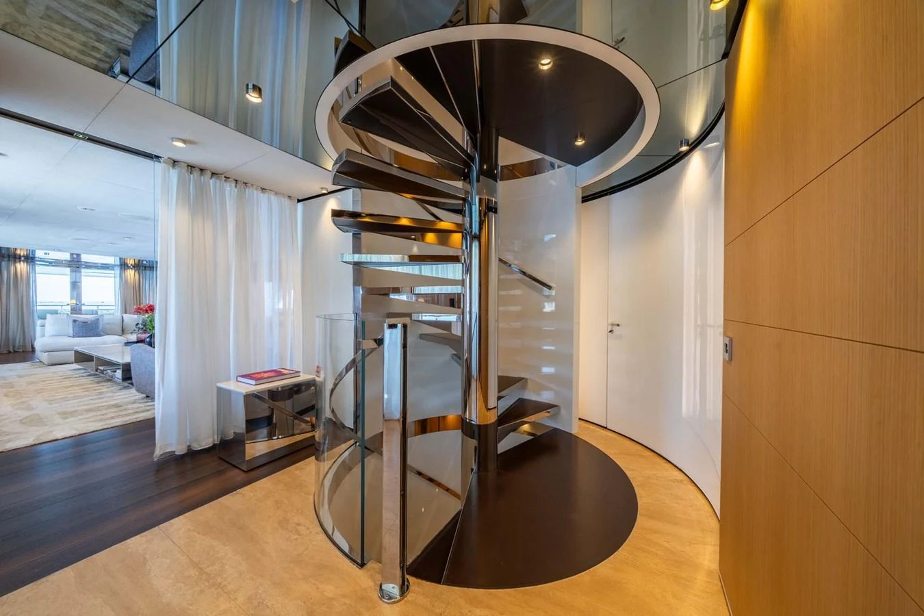 A luxurious spiral staircase with modern design elements connects the levels of this yacht's interior. aboard MR. T Yacht for Sale