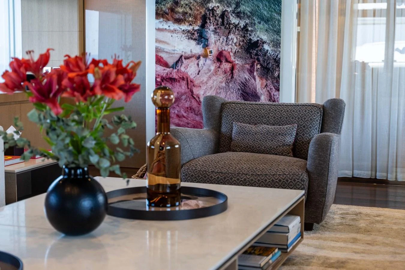 The yacht's interior features a cozy seating area with a plush armchair and a stylish coffee table adorned with decorative items. aboard MR. T Yacht for Sale